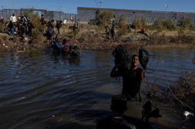 Siviller Ciudad Juarez sınırından bir nehri geçerek göç zorluklarının ortasında gerekli şeyleri taşıyorlar..