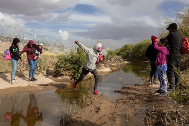 Siviller Ciudad Juarez sınır çiti yakınlarındaki çamurlu sularda dolaşarak göç sorunlarını vurguluyor.
