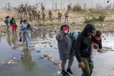 Siviller Ciudad Juarez sınırı yakınlarında sınır devriyelerinin tetikte beklediği çamurda yürüyorlar..