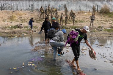 Siviller Ciudad Juarez 'deki sığ bir nehirde yol alıyorlar, sınır muhafızları tarafından gözden kaçırılıyorlar..