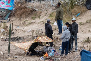 Siviller Ciudad Juarez sınırındaki dikenli tellerin yanındaki derme çatma bir sığınağın yakınında toplanıyorlar..