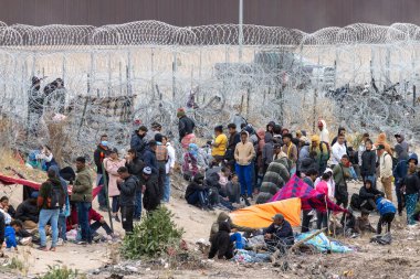 Gruplar Ciudad Juarez sınırında toplandı. Yüksek çitler ve dikenli tellerle işaretlenmiş dokunaklı bir göç sahnesi..