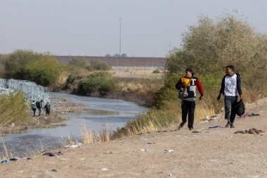 Ciudad Juarez yakınlarındaki Rio Grande boyunca akordeon tellerinin yanından geçen iki kişi göç sorunlarını vurguluyor..