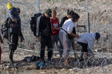 Ciudad Juarez yakınlarında dikenli tellerden geçen göçmenler..