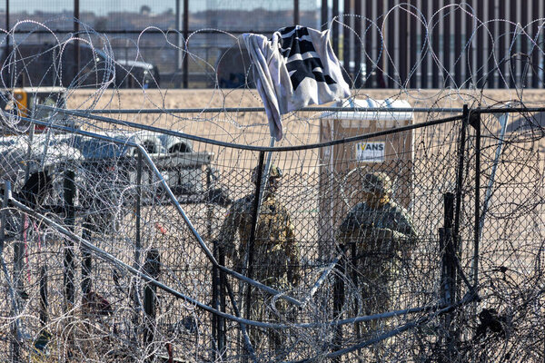 Concertina wire tops a fence with discarded clothing at Ciudad Juarez, a poignant symbol of the migration crisis.