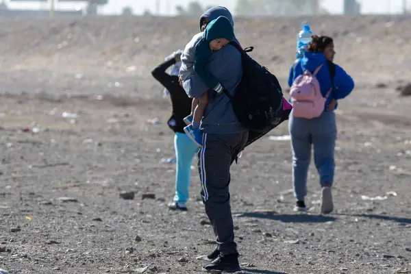 Aralarında bir çocuk taşıyıcısının da bulunduğu siviller, göç sorunlarının simgesi olan Ciudad Juarez manzarasını aşıyorlar..