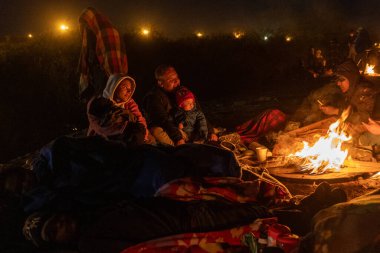 Ciudad Juarez sınırındaki geçici bir kampta aileler ateşin etrafında toplanıyor..