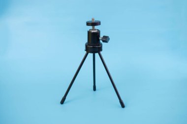 Mavi arka planda, çelik kılıflı ve top kafalı siyah mini tripod..