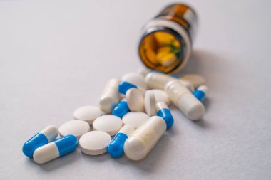 Beyaz ve mavi reçeteli haplar ve reçeteli ilaç şişesinden dökülen kapsüller, tıbbi tedavi kavramı