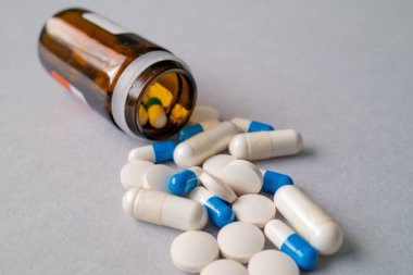 Beyaz ve mavi reçeteli haplar ve reçeteli ilaç şişesinden dökülen kapsüller, tıbbi tedavi kavramı