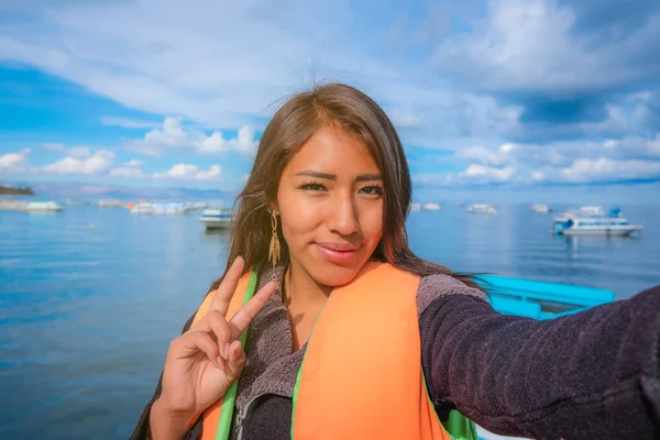happy latin woman on vacation taking selfie on lake titicaca in 