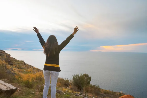 happy young woman spreading her arms in joy watching the sunset 