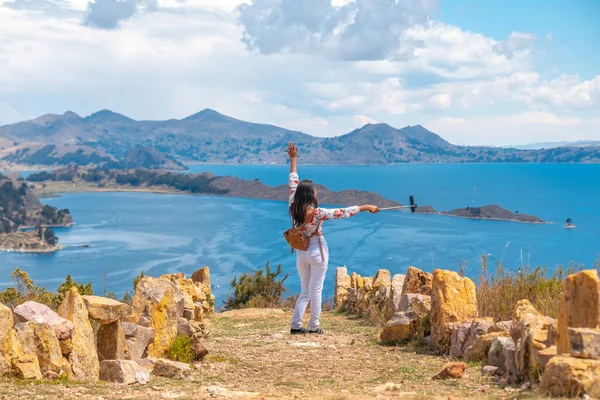 Latin woman on vacation taking selfie on Sun`s Island with Lake 