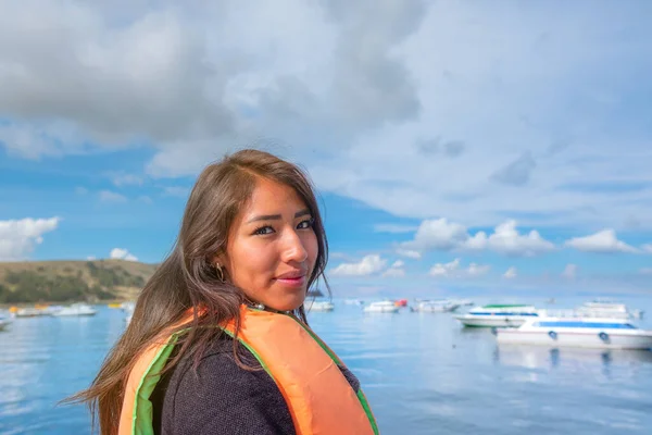 smiling young latin woman sightseeing in a boat on the shores of lake titicaca in bolivia
