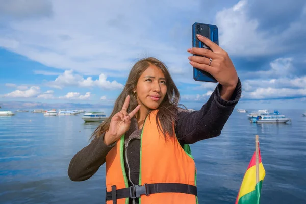 young hispanic woman on vacation taking selfie on a boat with la