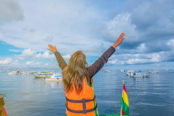young woman with arms up admiring and enjoying lake titicaca in 