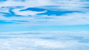 Bir uçak penceresinden bulutlu manzara. Küçük bulutlu mavi gökyüzü arkaplanı.