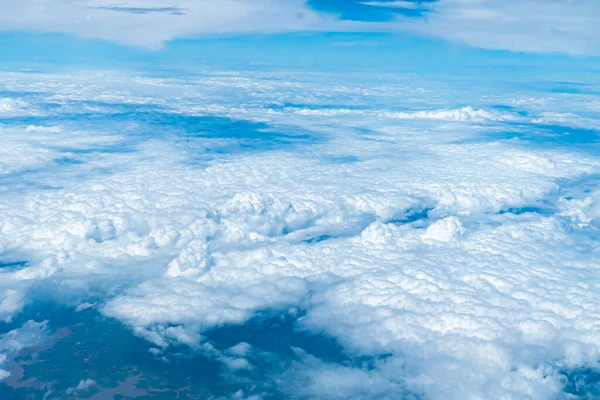 Bir uçak penceresinden bulutlu manzara. Küçük bulutlu mavi gökyüzü arkaplanı.