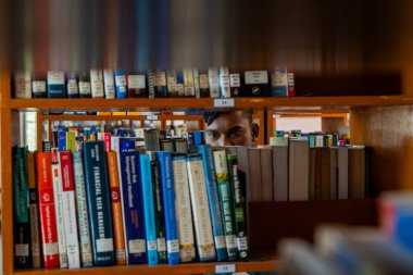 Pek çok rafı ve kitabı olan bir kütüphane, perspektifi azalan ve sade alan