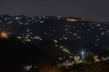 Ranikhet Uttarakhand 'da parlayan fenerlerle dolu bir dağ köyünün gece görüşü.