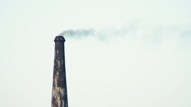 Hindistan 'ın kırsal kesimindeki geleneksel tuğla fırınının gökyüzüne yoğun duman salmasını tasvir eden sert ve güçlü bir görüntü.. 