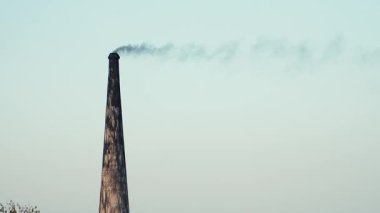 Hindistan 'ın kırsal kesimindeki geleneksel tuğla fırınının gökyüzüne yoğun duman salmasını tasvir eden sert ve güçlü bir görüntü.. 