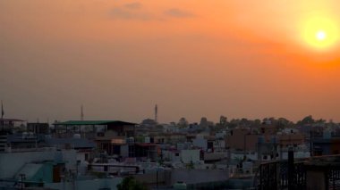 Dehradun, Uttarakhand 'da gün batımını gösteren 4K görüntüler. Kamera düzgün bir şekilde sağa döner, parlayan gökyüzünü, ılık ışığı ve yumuşak şehir siluetlerini ortaya çıkarır..