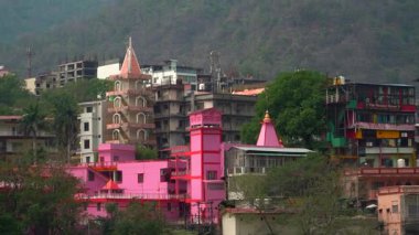 Uttarakhand, Rishikesh 'teki Ganges Nehri. Klip, Uttarakhand 'ın Rishikesh kentinde 10.05.2025 manzaralı bir arka planda beyaz su akıntılarında gezinen maceraperestlerin heyecanını yakalıyor. Hindistan 