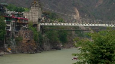 Uttarakhand, Rishikesh 'teki Ganges Nehri. Klip, Uttarakhand 'ın Rishikesh kentinde 10.05.2025 manzaralı bir arka planda beyaz su akıntılarında gezinen maceraperestlerin heyecanını yakalıyor. Hindistan 