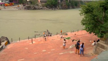Uttarakhand, Rishikesh 'teki Ganges Nehri. Klip, Uttarakhand 'ın Rishikesh kentinde 10.05.2025 manzaralı bir arka planda beyaz su akıntılarında gezinen maceraperestlerin heyecanını yakalıyor. Hindistan 