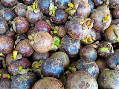 Bir demet tatlı mor mangosteen meyvesi, çeşitli meyveler ahşap masaya konmuş doğal arka planda meyve dükkanında satılık.