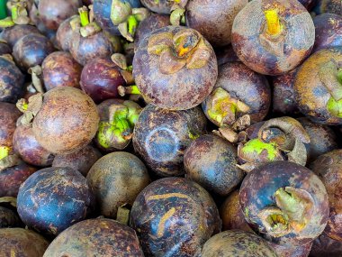 Bir demet tatlı mor mangosteen meyvesi, çeşitli meyveler ahşap masaya konmuş doğal arka planda meyve dükkanında satılık.
