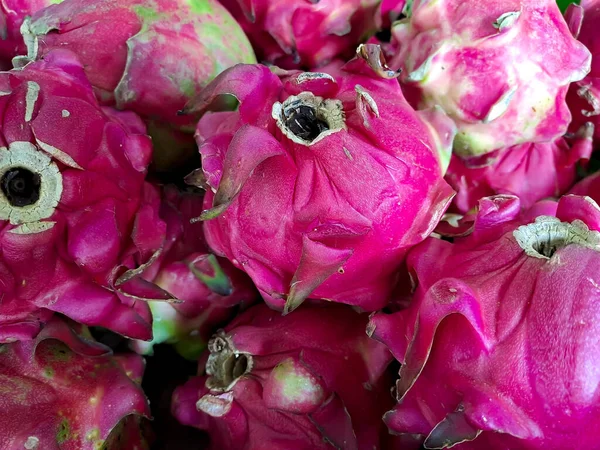 bunch of red sweet dragon fruit, several big sweet red dragon fruit put on wooden table on natural background for sale in fruit shop