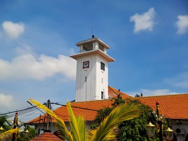 Endonezya, Doğu Java 'da, Madiun' da güzel mavi gökyüzü olan eski beyaz bir binada büyük bir duvar saati.