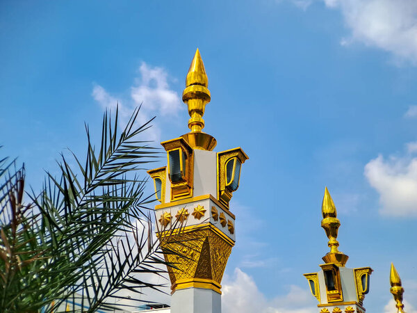 brown gold white color mosque minaret with arabic architecture in madiun indonesia park, sunny weather
