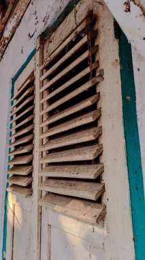 Açık bejle boyanmış bir çift eski, ahşap pencere panjuru..