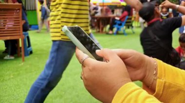 Canlı sarı elbiseli bir kadın akıllı telefonuyla modern hayatın ve dijital bağlantının özünü yakalıyor. Yaşam tarzı videoları, sosyal medya içeriği ve teknoloji için mükemmel.