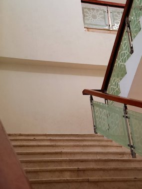 İslami geometrik desenlere sahip karmaşık cam panelleri olan modern merdiven çağdaş bir camide asma kata çıkıyor.