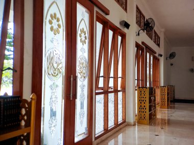 Karmaşık İslami el yazısı içeren vitray pencereli bir caminin iç görünümü