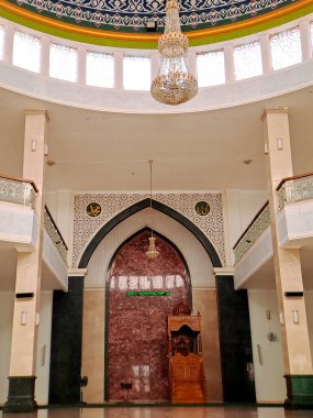 Bir caminin merkez koridoruna bakmak, mihrab 'ın (dua yeri) ve karmaşık mimari detayların sergilenmesi. Bu fotoğraf dingin ve ruhani atmosferi yakalar.