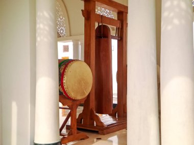 Geleneksel İslami davul kazılmış ve cami avlusunda asılı duran bir gong sehpası, inananları namaza çağırmaya hazır.