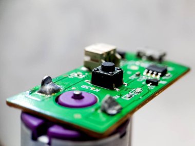 Bir düğme, USB portu ve mikroçipler de dahil olmak üzere çeşitli elektronik bileşenleri olan yeşil devre kartı