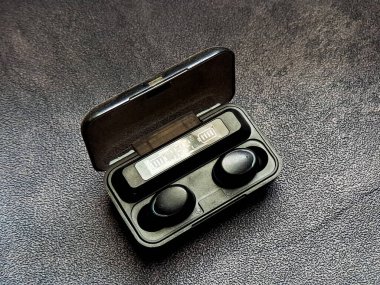 Kablosuz kulaklıklar açık şarj çantasının içinde duruyor. Batarya seviyesi, tarafsız bir arkaplanda açıkça görülüyor. Ses keyfine ve rahatlığına hazır..