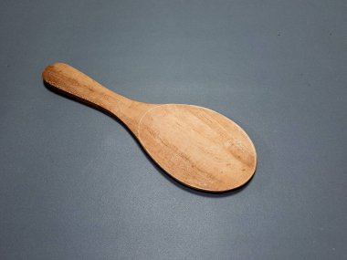 Basit bir ahşap kaşık zarif bir şekilde bir stüdyo ortamında koyu gri bir yüzeye dayanır..