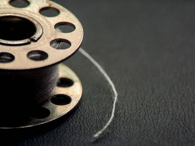 Beyaz iplikli bir dikiş kutusu ilgi çekici bir görsel anlatı sunar, tekstil ekipmanları ve ince güzelliği, seçici odak ve karanlık arka planla geliştirilmiştir.. 