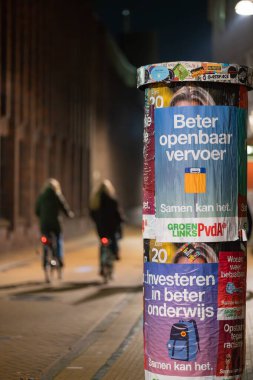 Groningen, Hollanda - 117 2023: Kamu Seçimleri İçin Kamu Kampanyası Bisikletçi Geçip Giderken, Reklam Sütunları Üzerine Posterler