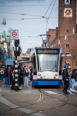 Amsterdam, Hollanda - 1 Nisan 2024: Busy Street Stop 'ta Tarihi Mimariyle Banliyö Tramvayı