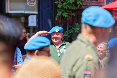 Den Haag, Hollanda - 29 Haziran 2024: Hollanda Veteranendağ askeri geçidi sırasında mavi bereli Hollandalı gazi arkadaşlarını selamladı