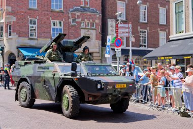 Den Haag, Hollanda - 29 Haziran 2024: Askeri Hollanda aracı Fennek, Veteranendağ yürüyüşü sırasında tezahürat yapan kalabalıkla birlikte şehir caddesinden geçiyor