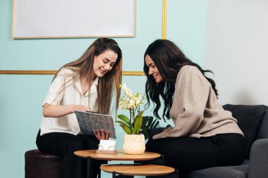 Güzellik salonundaki resepsiyondaki genç bayan hizmetleri ve fiyatları öğreniyor.